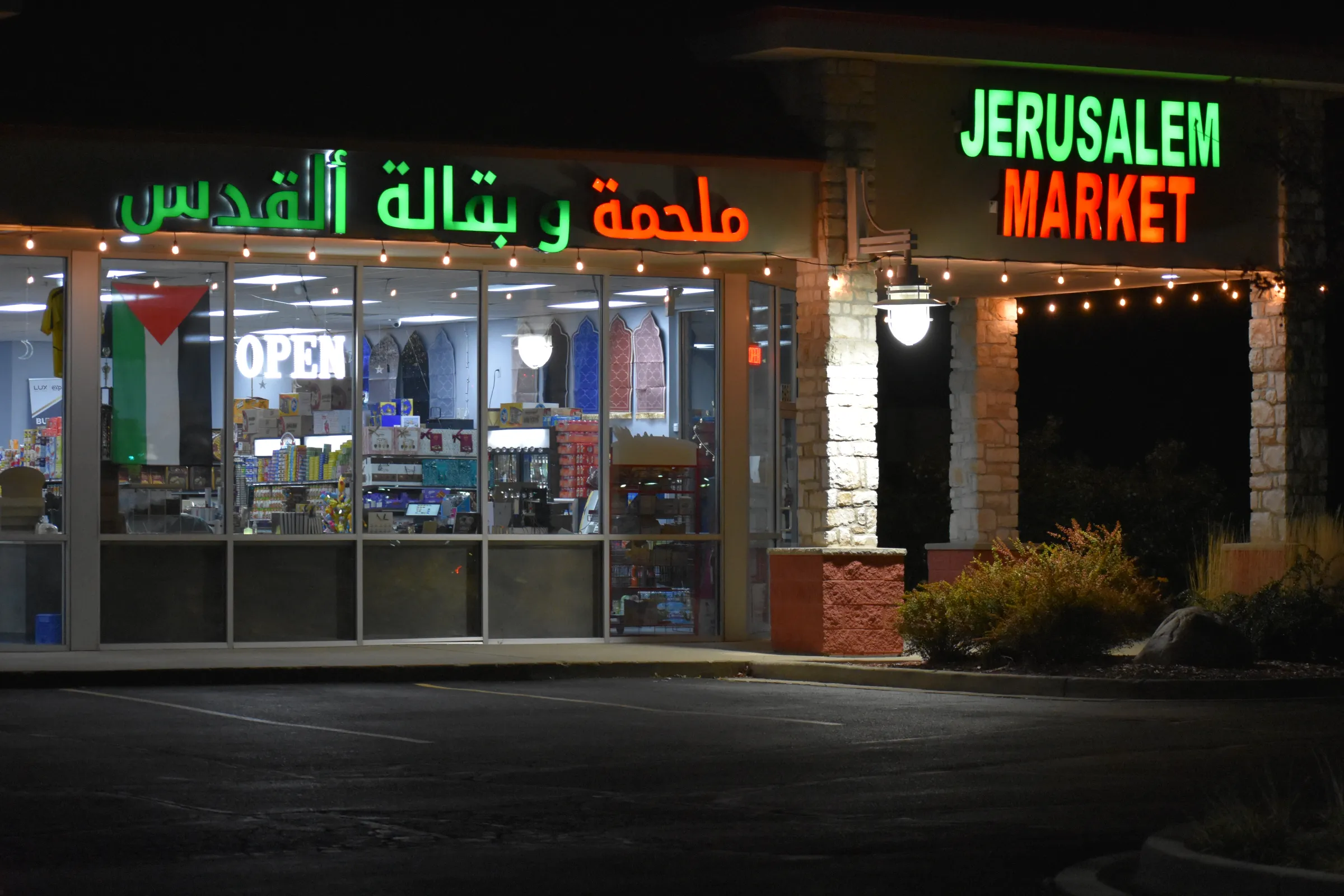 Jerusalem Market's storefront at night, its English and Arabic signs lit above the front windows